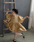 a little girl in a brown dress and black hat