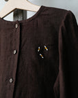 A brown button-up shirt with a small embroidered bee design on the front.