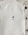 A close-up view of a white shirt with a small embroidered anchor symbol on the front.