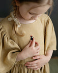 a little girl in a brown dress and a black hat