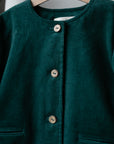 A close-up view of a dark green button-down jacket with three buttons and two pockets.