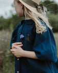 a little girl wearing a hat and holding a flower
