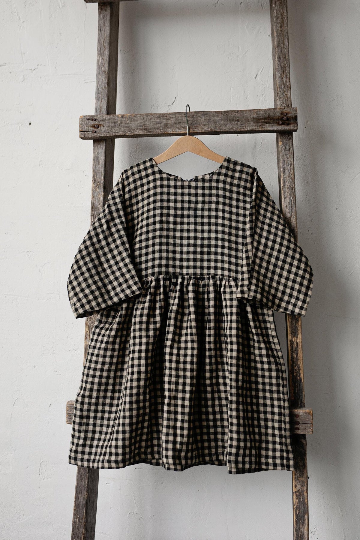a black and white checkered dress hanging on a wooden ladder