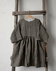 a black and white checkered dress hanging on a wooden ladder