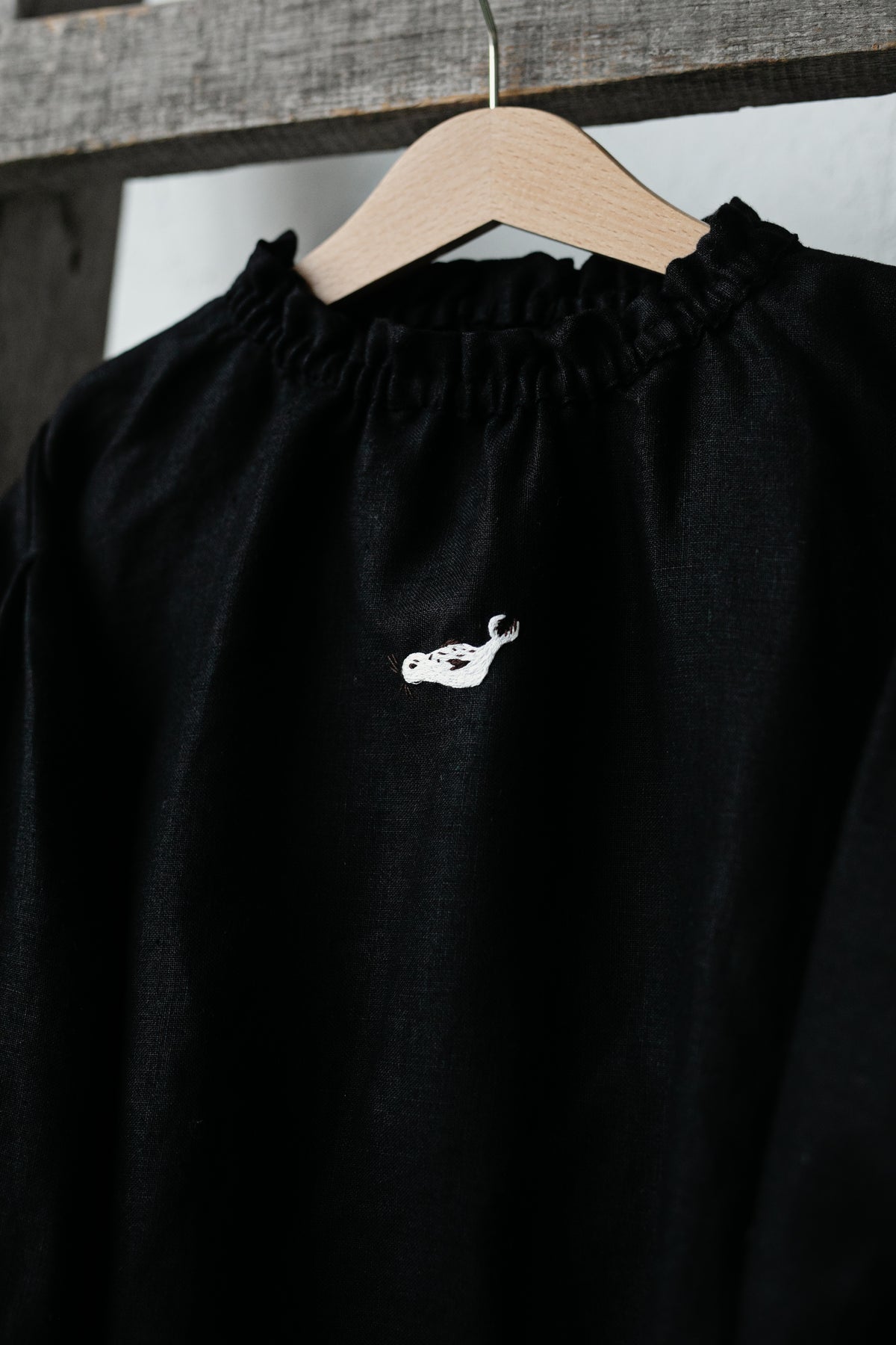 A black shirt with a white embroidered design on the front.
