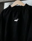 A black shirt with a white embroidered design on the front.