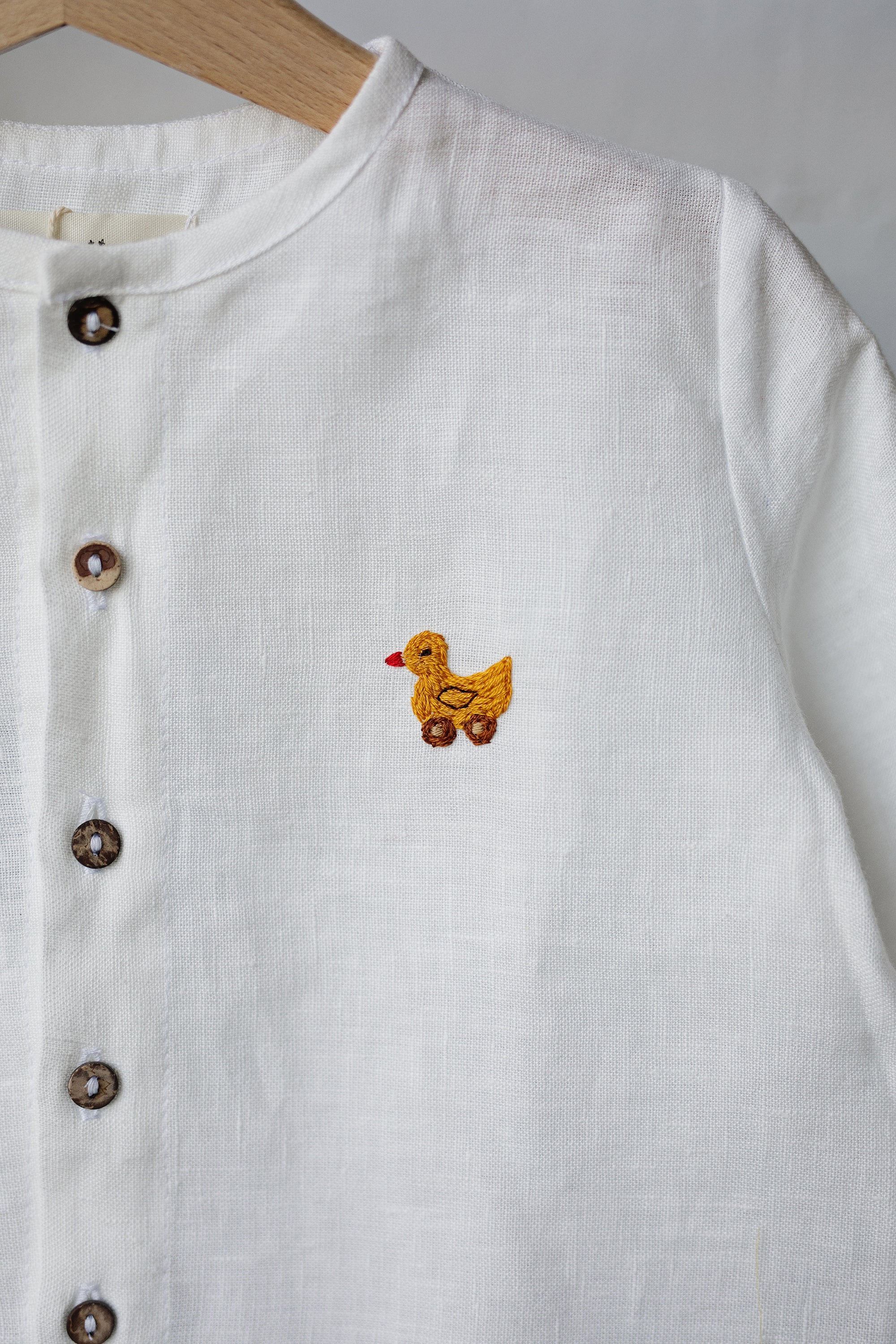 A white button-down shirt with a small embroidered duck on the front.