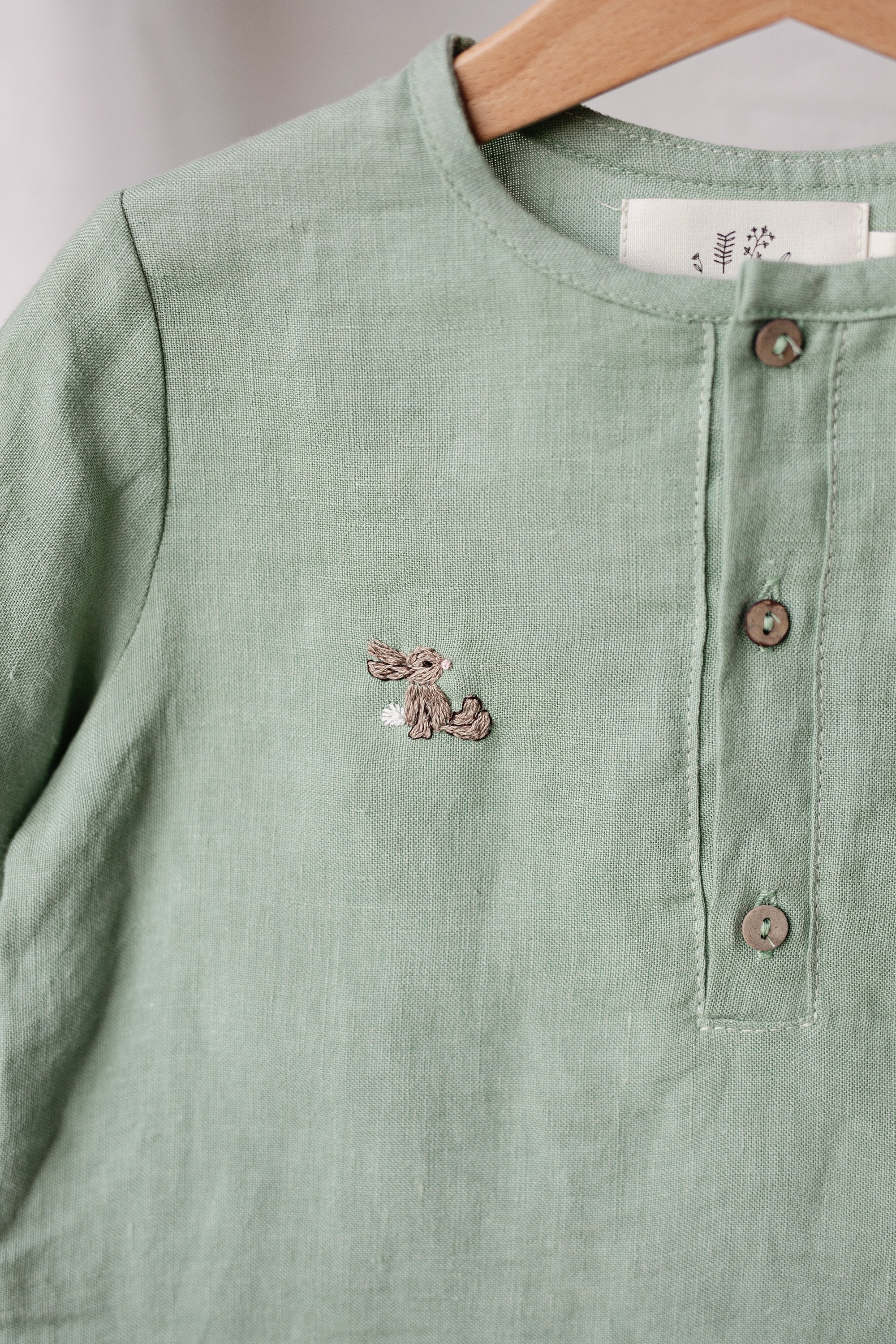 A light green button-down shirt with a small embroidered rabbit design on the front.