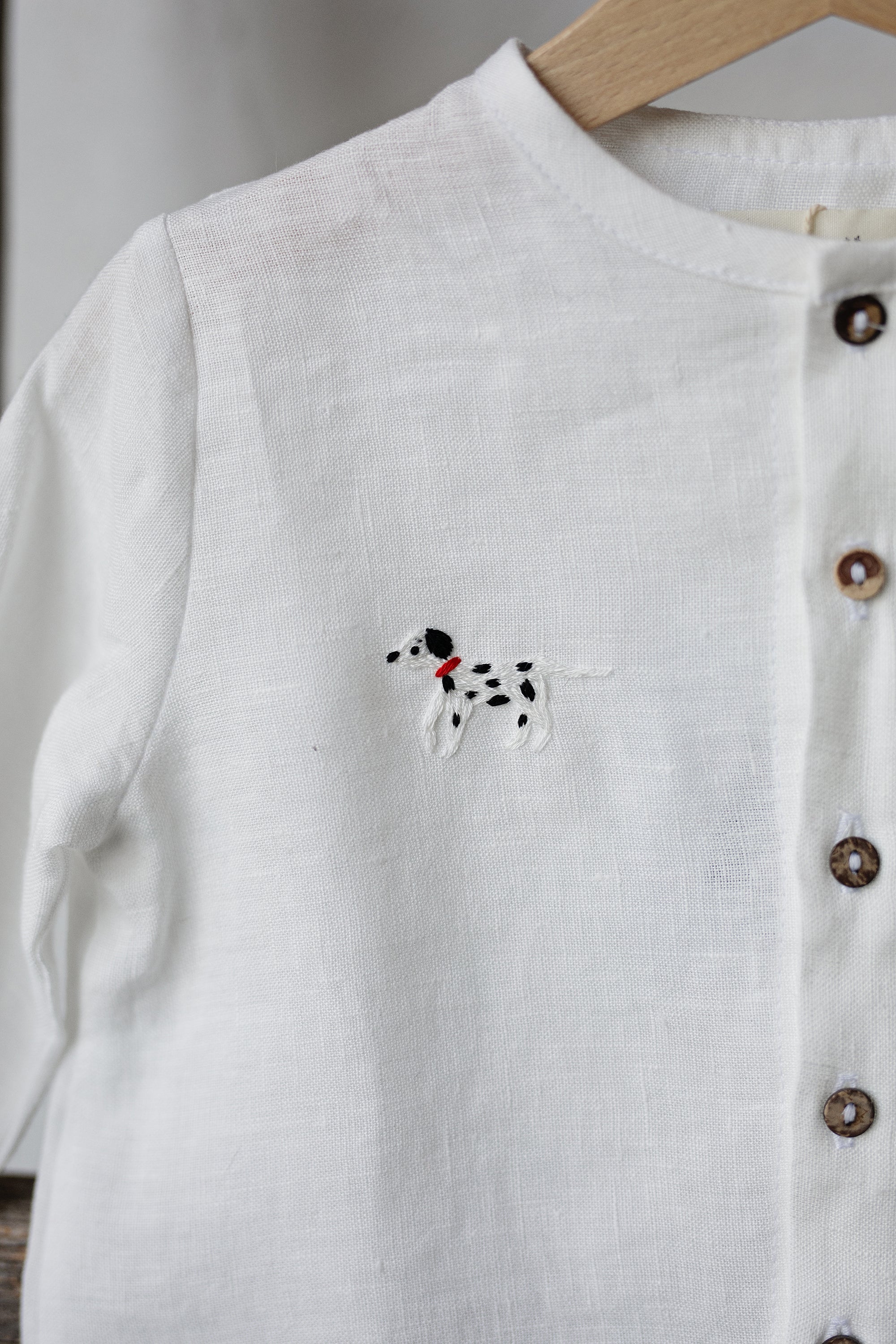 A white button-up shirt with a small embroidered dog design on the front.