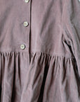 A close-up view of a pink fabric with a ruffled collar and three buttons.