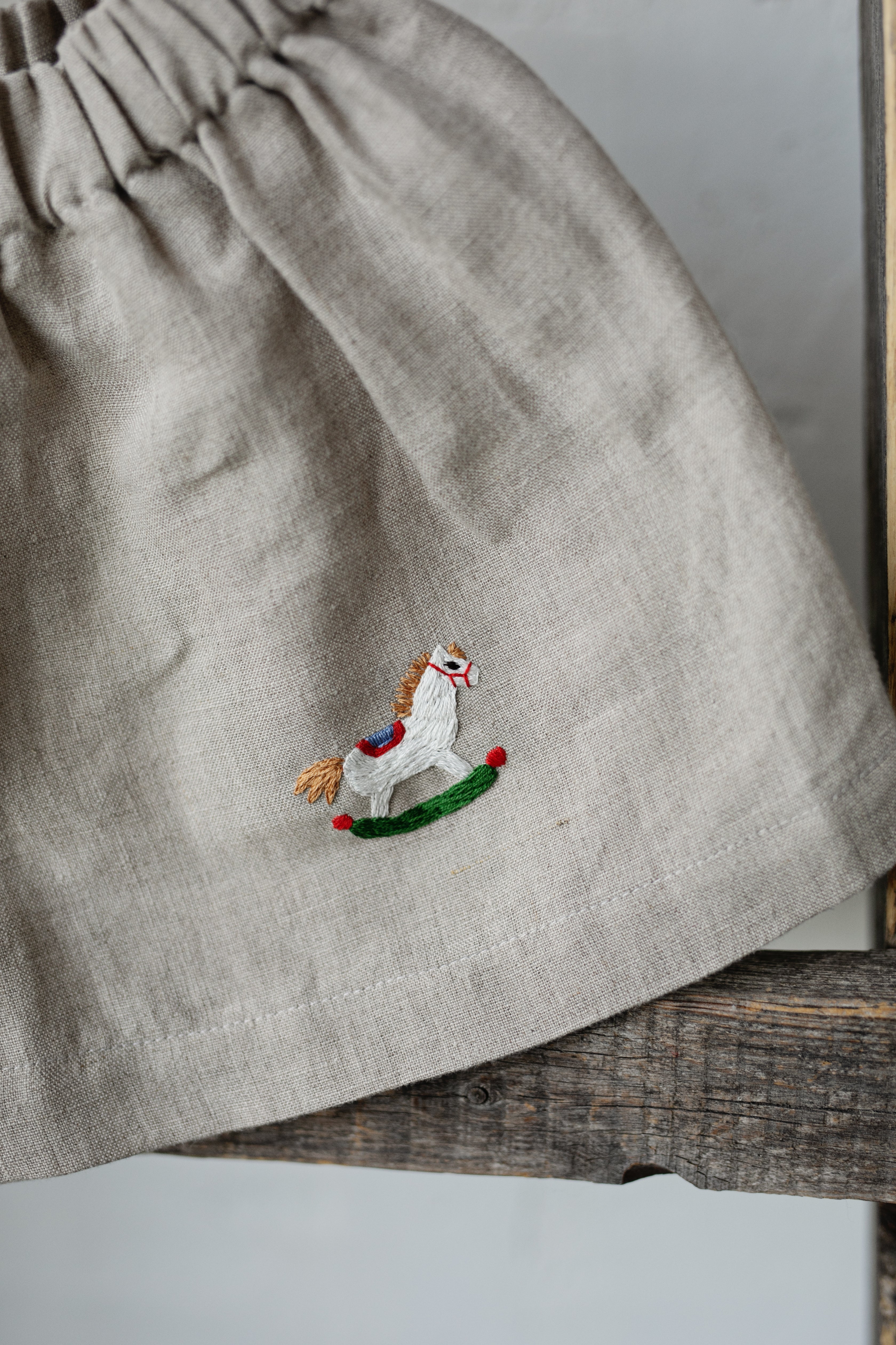 a grey skirt with a small embroidered image of a horse on it.
