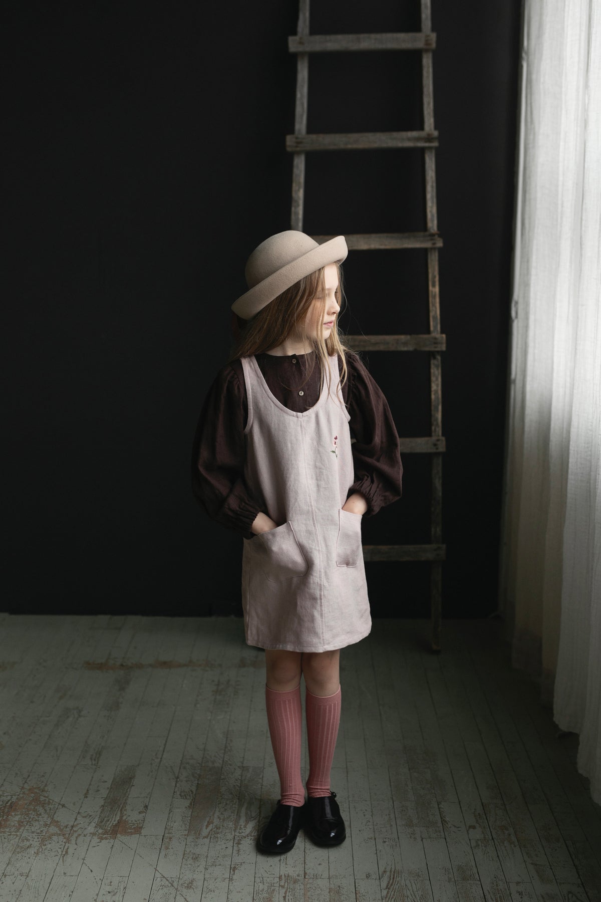 a little girl standing in front of a ladder