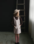 a little girl standing in front of a ladder