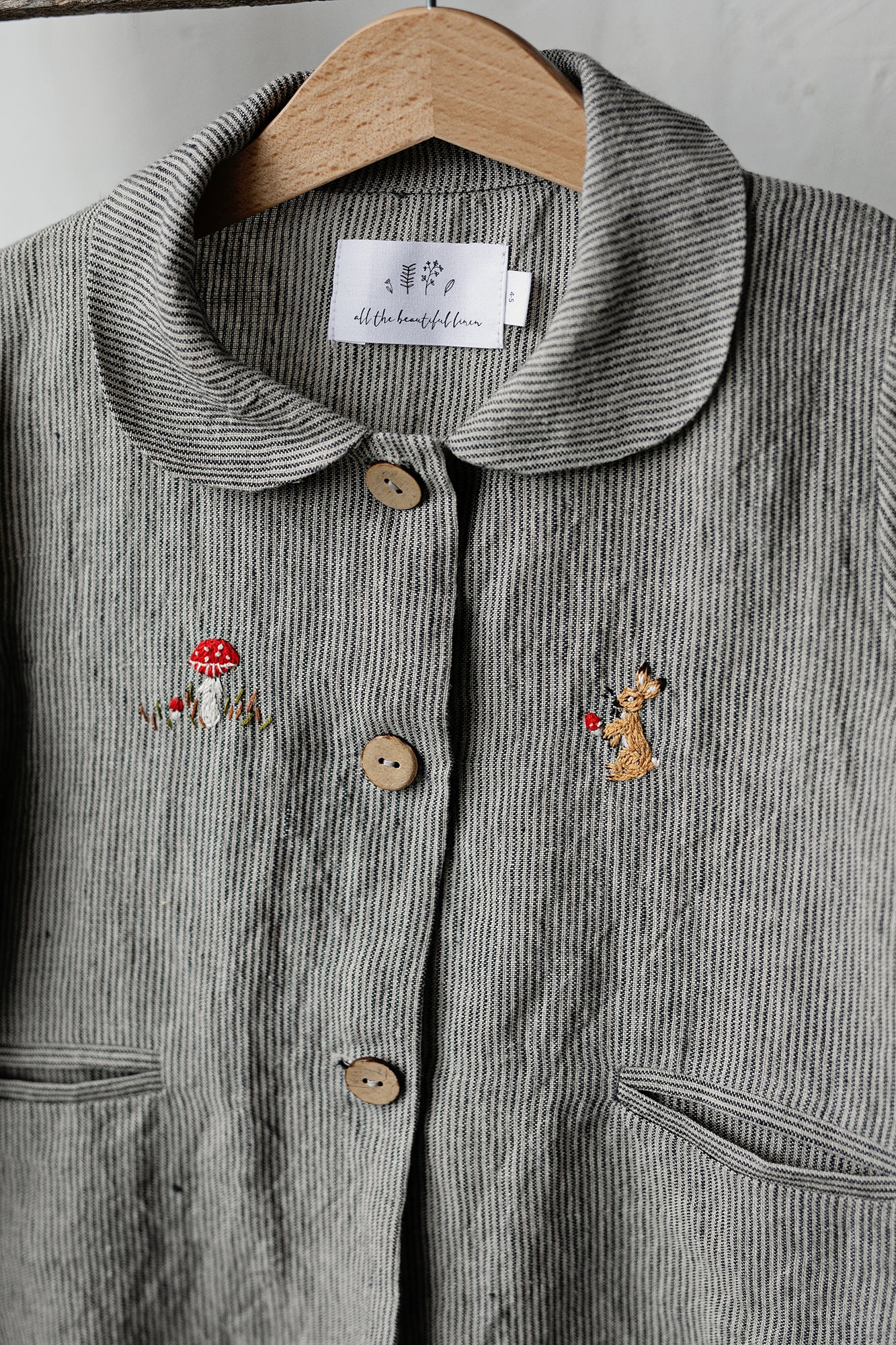 a gray jacket with small embroidered animals on it