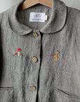 a gray jacket with small embroidered animals on it