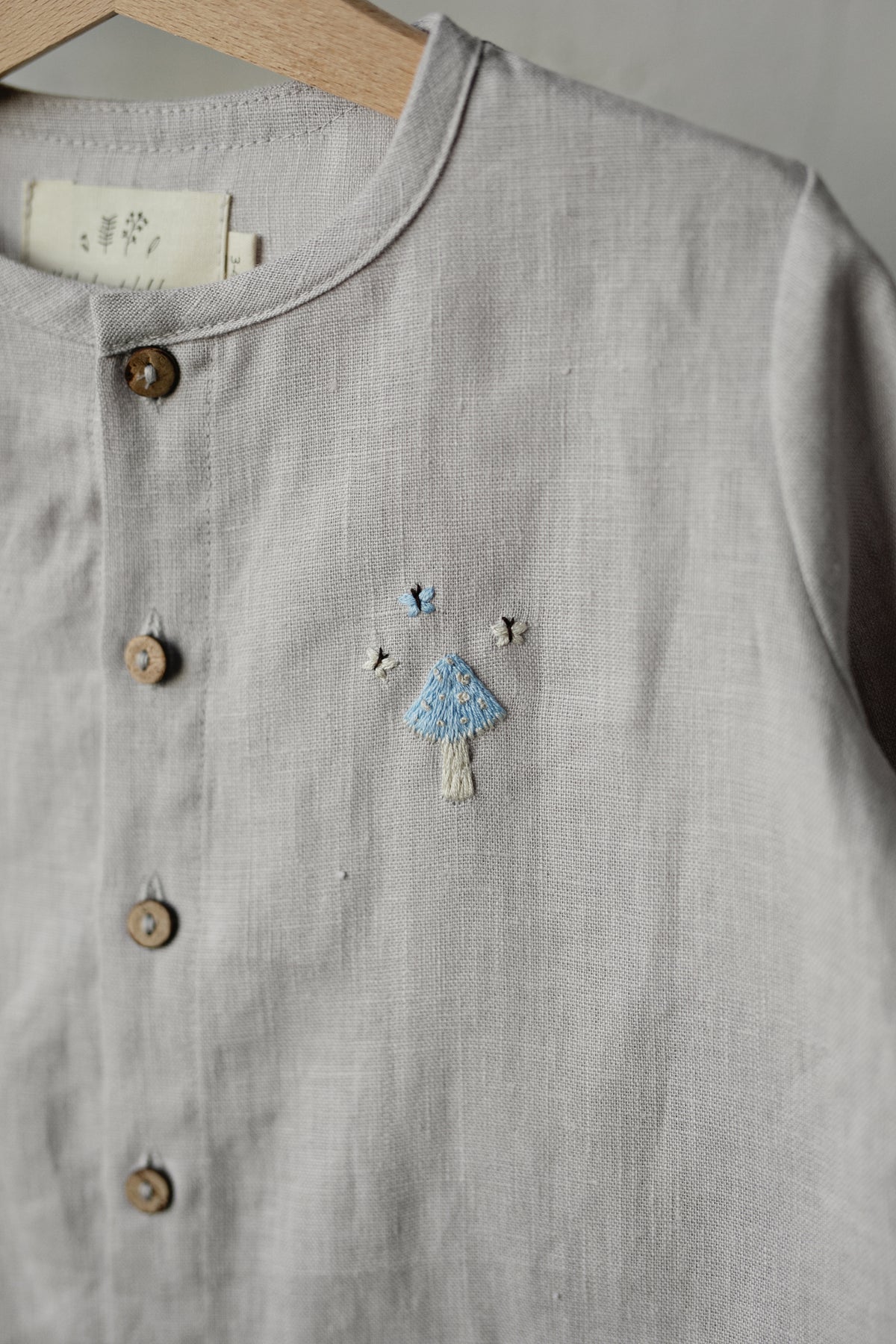 A gray button-up shirt with a small embroidered design on the front.