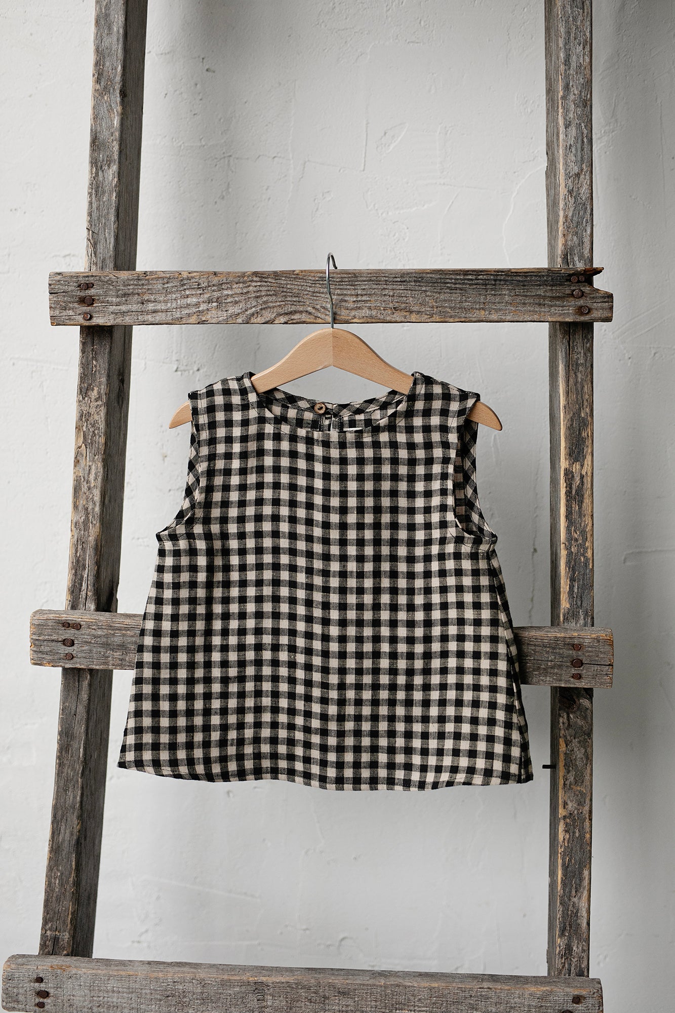 a black and white checkered dress hanging on a wooden ladder