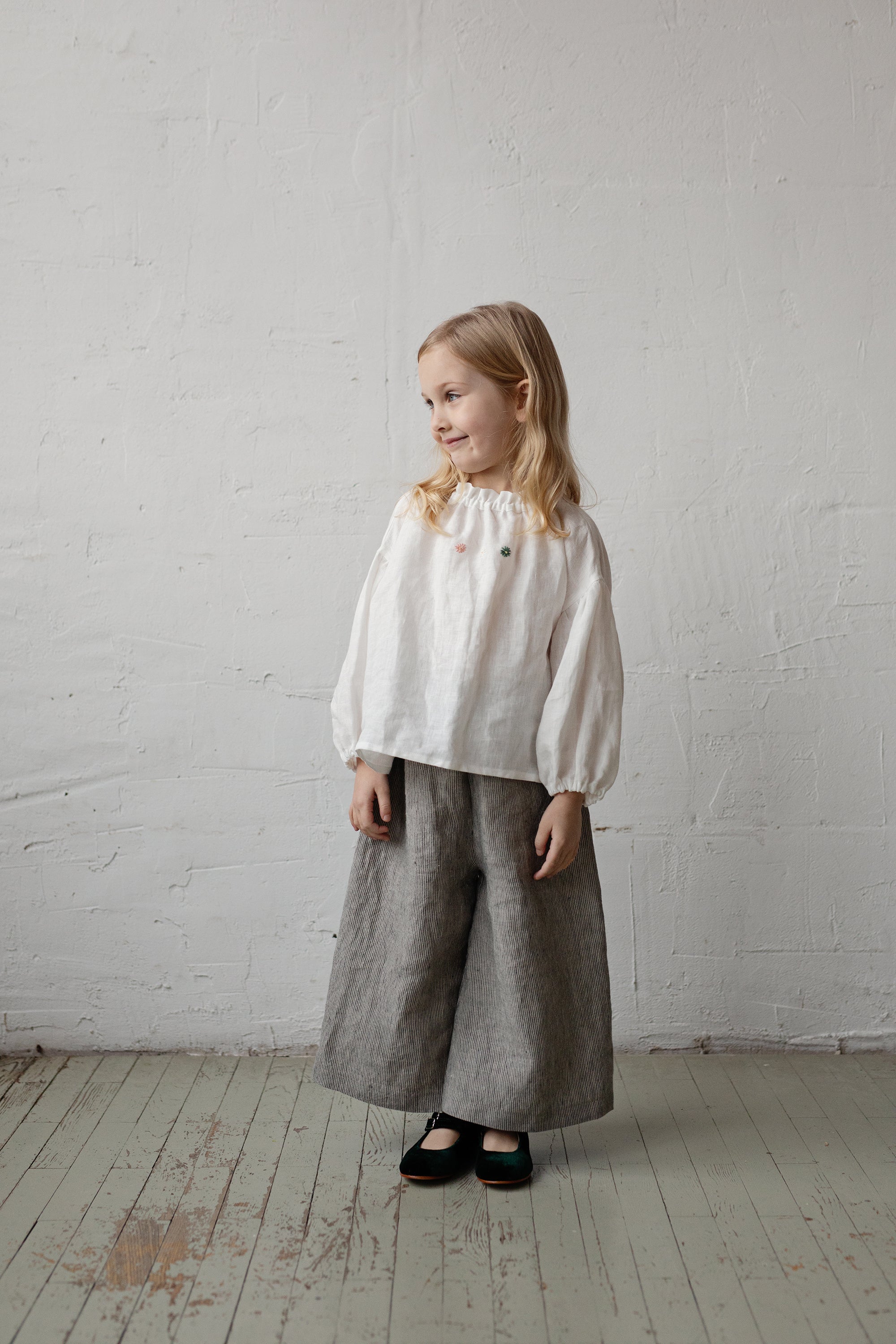 a little girl standing on a wooden floor