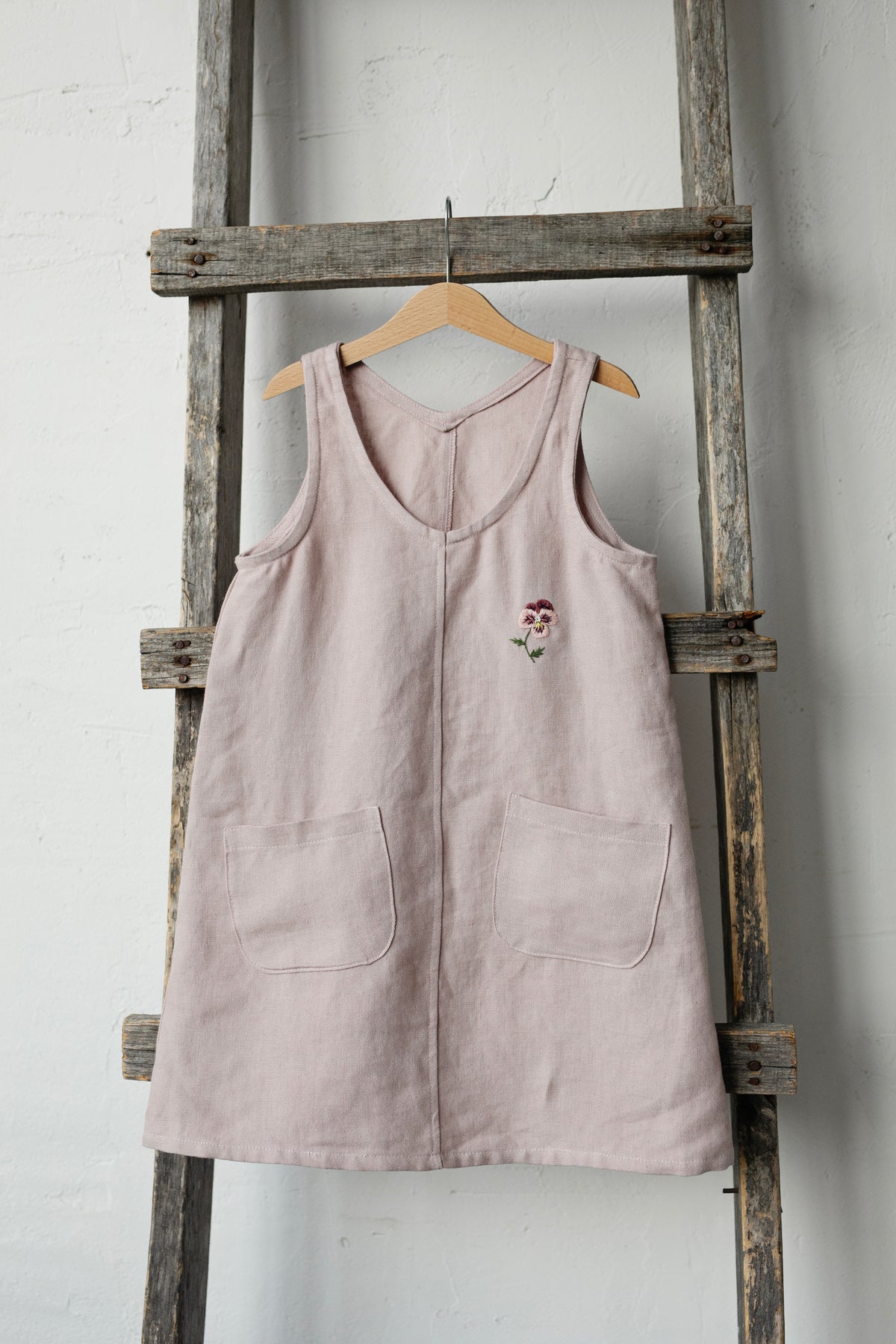 a pink top hanging on a wooden ladder