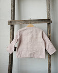 A wooden ladder with a pink polka dot shirt hanging from one of the rungs.