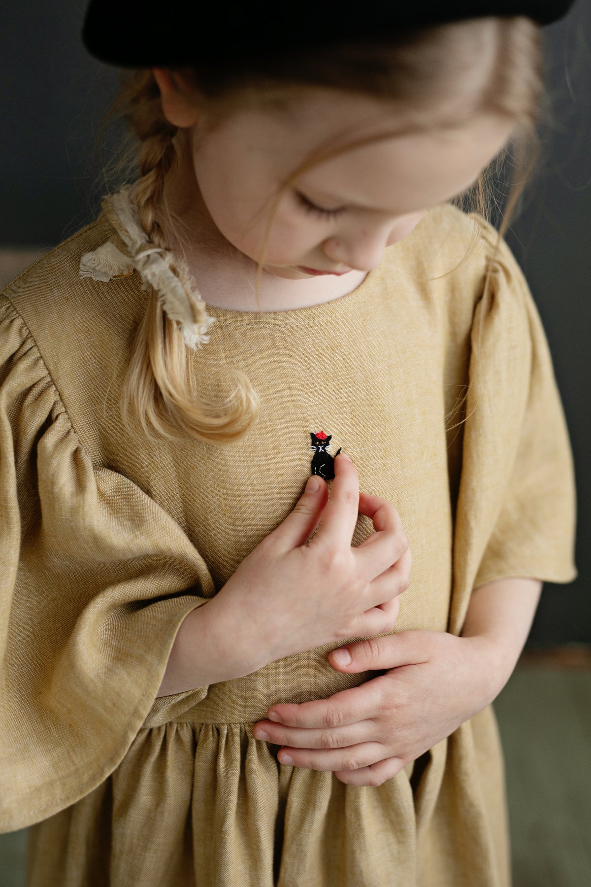 a little girl in a brown dress and a black hat