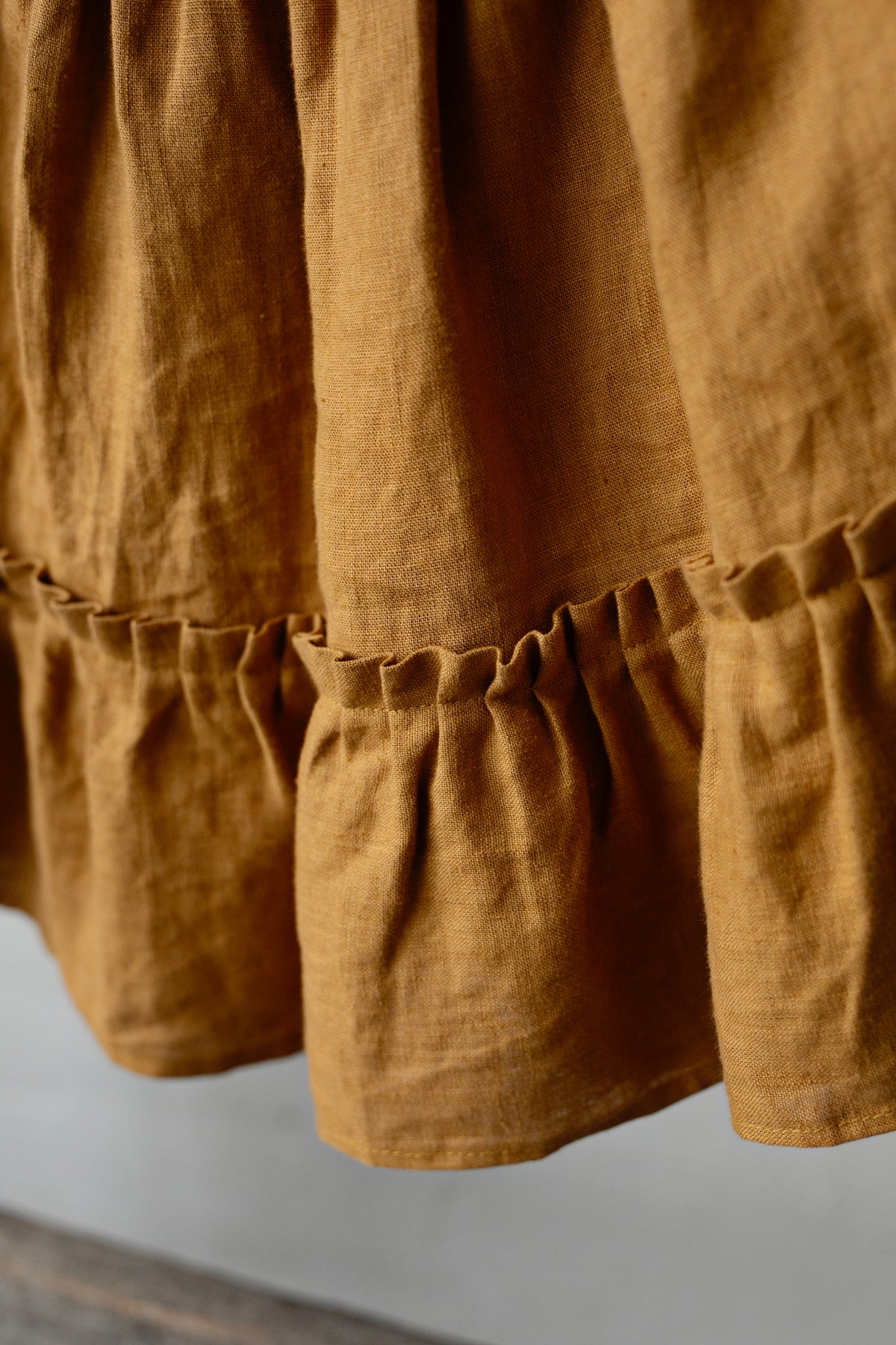 a close-up view of a brown fabric, possibly a skirt or a dress, with a ruffled or pleated design.