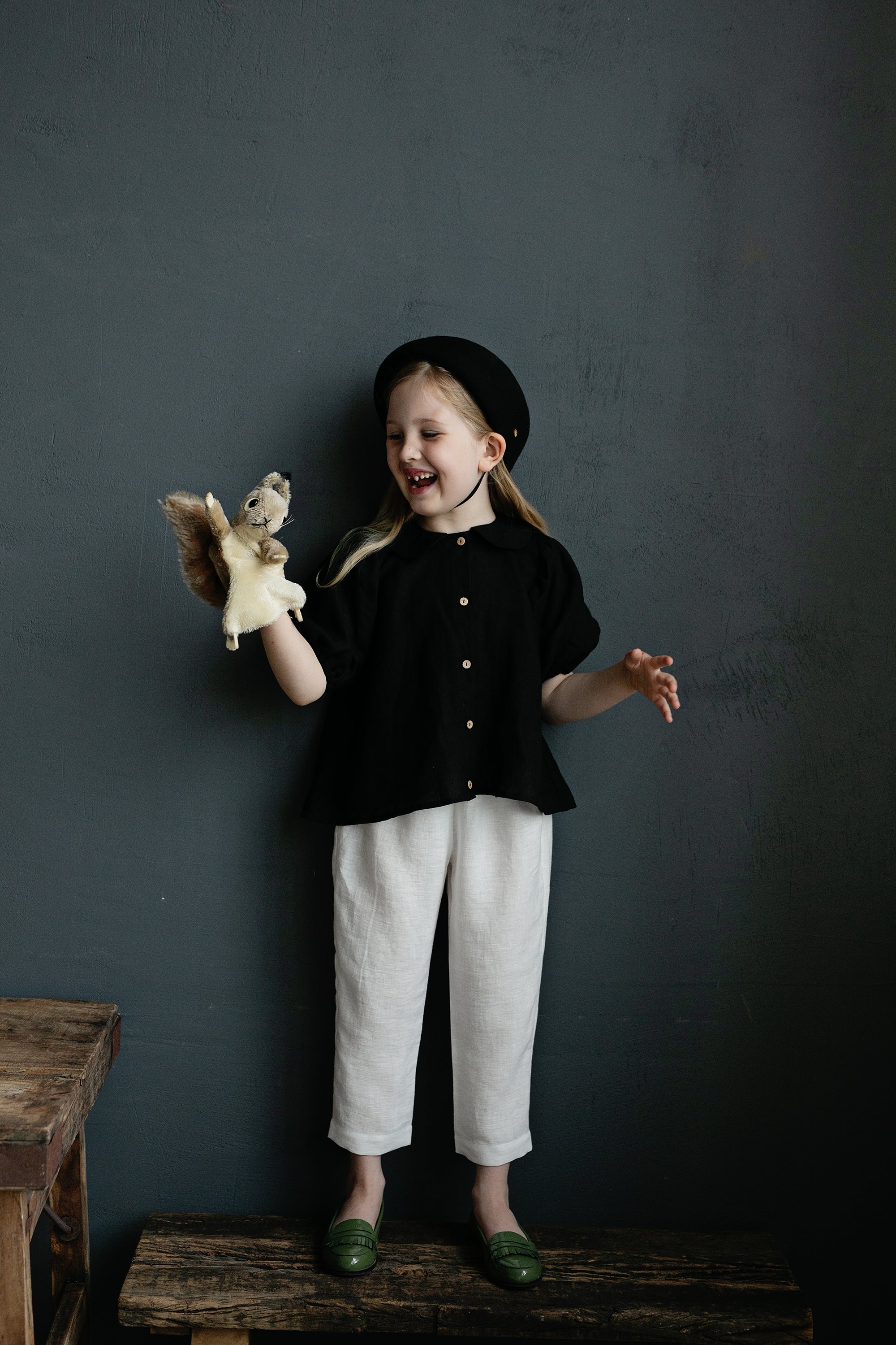 a little girl holding a stuffed animal on top of a wooden bench