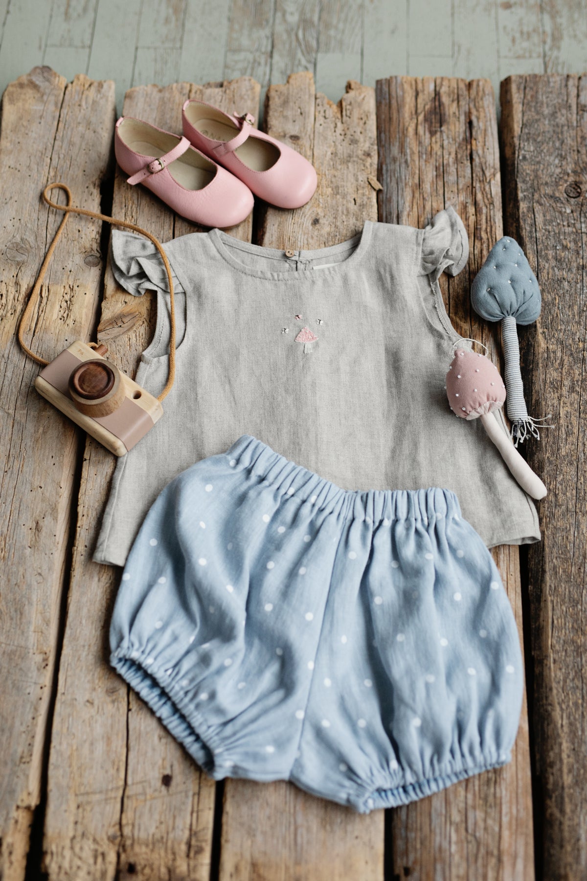 a baby's outfit and shoes on a wooden table