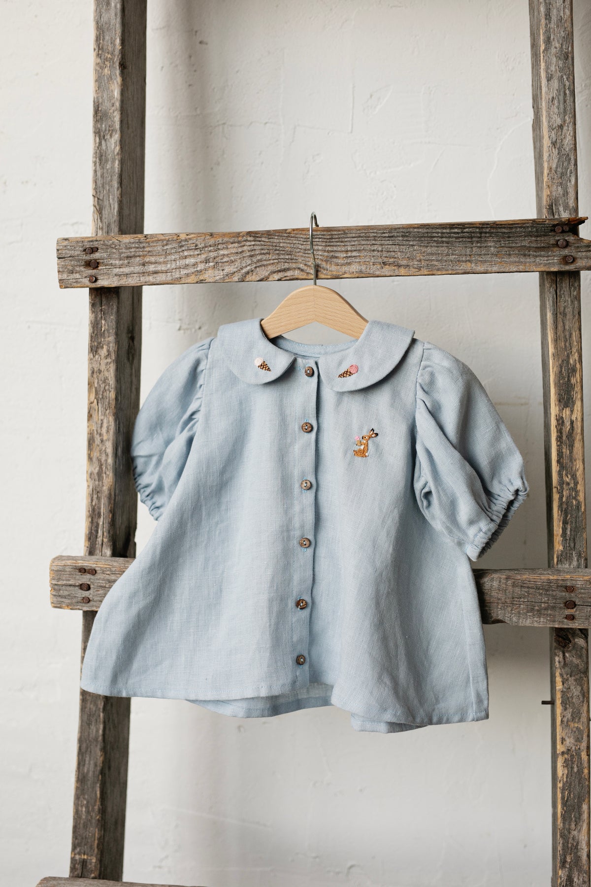 a blue shirt hanging on a wooden ladder