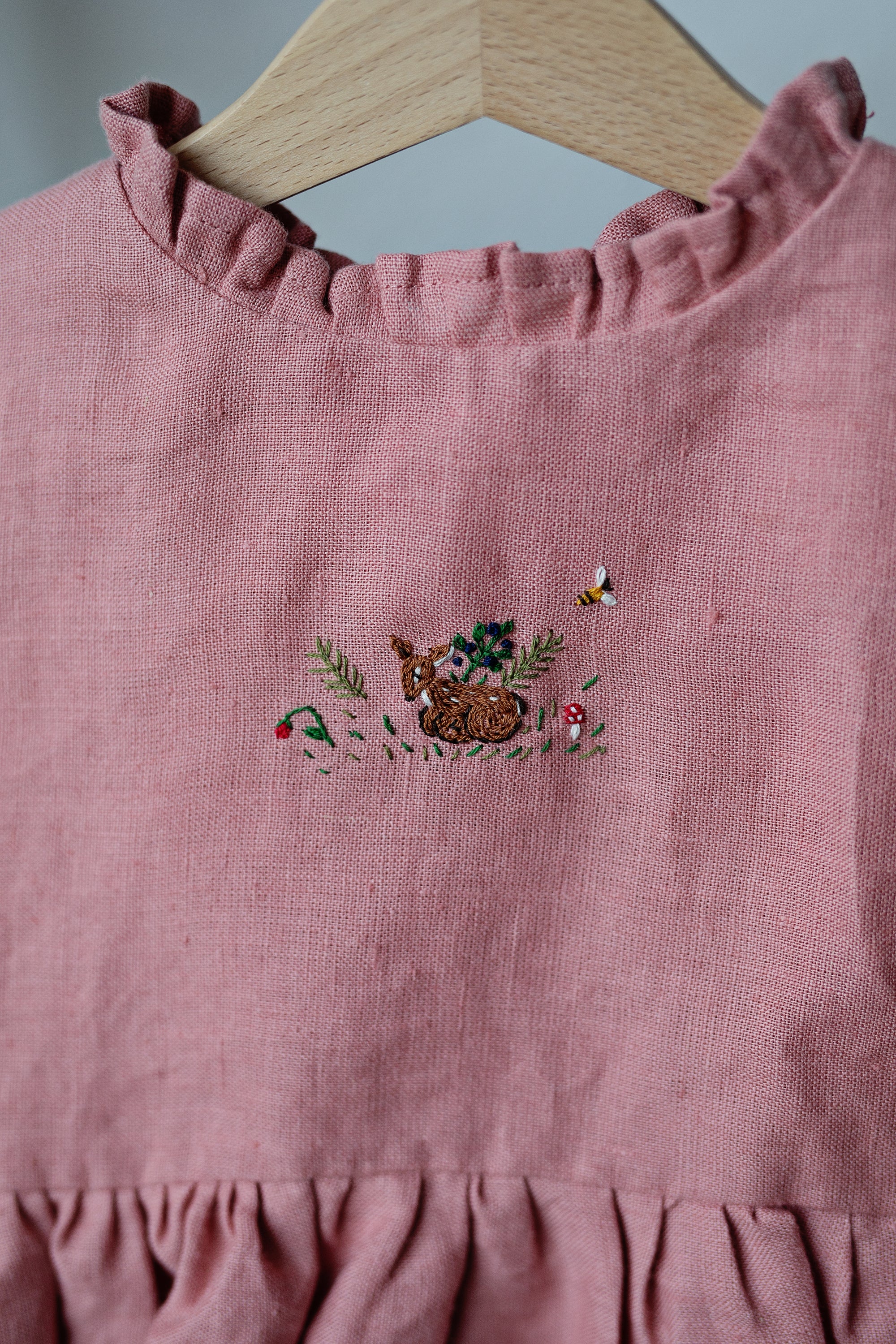 A pink dress with a small embroidered design of a rabbit and flowers on the front.
