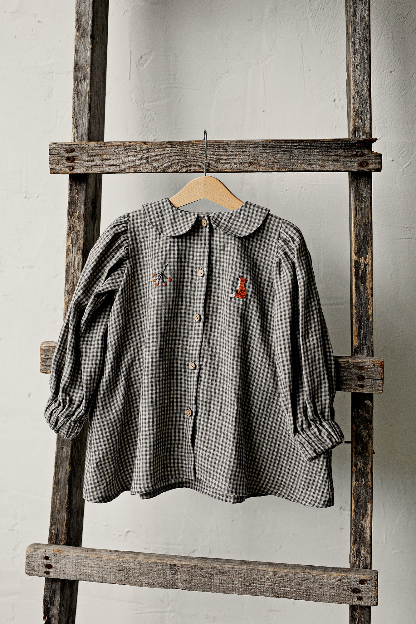 a black and white checkered shirt hanging on a wooden ladder