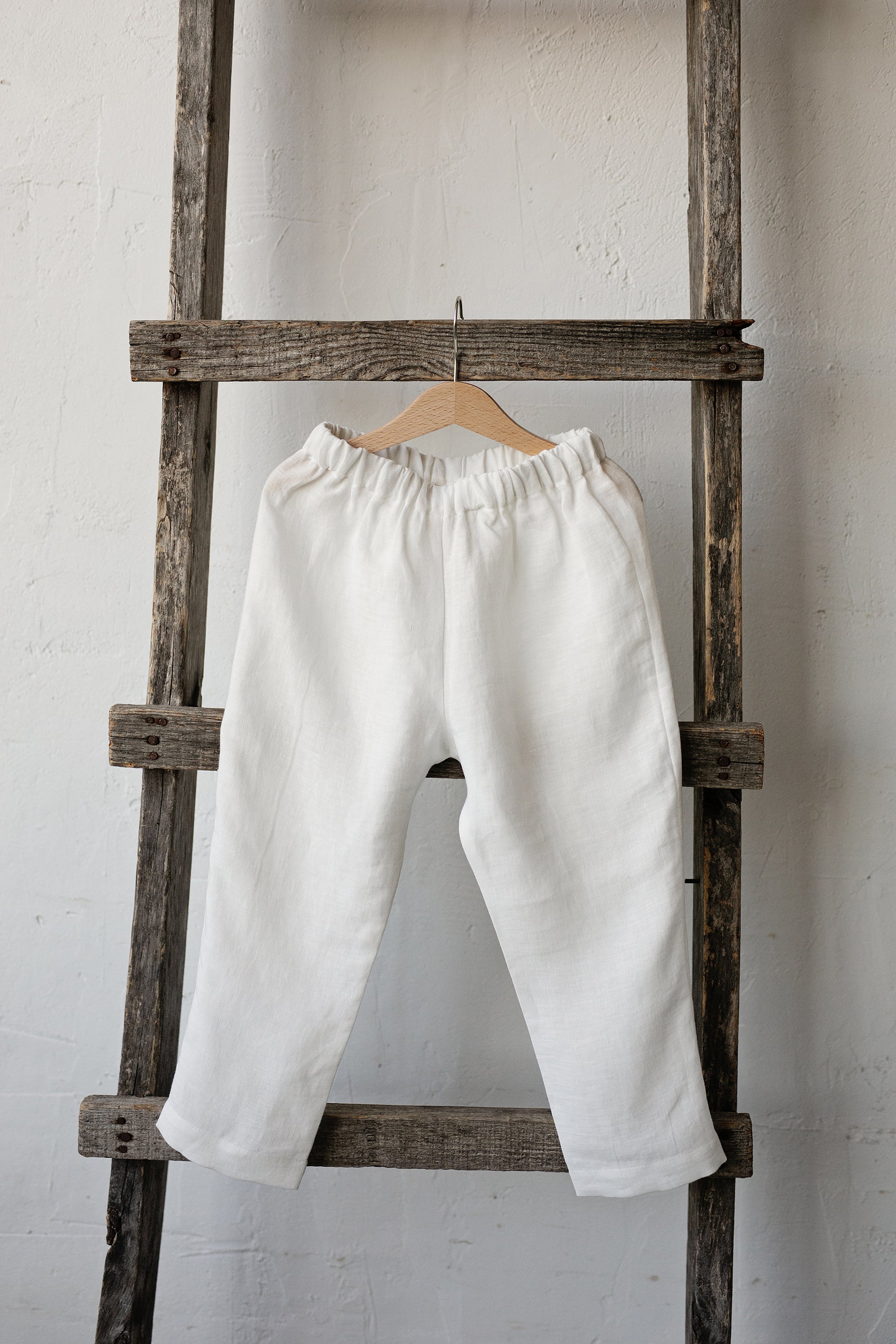 a white pair of pants hanging on a wooden ladder