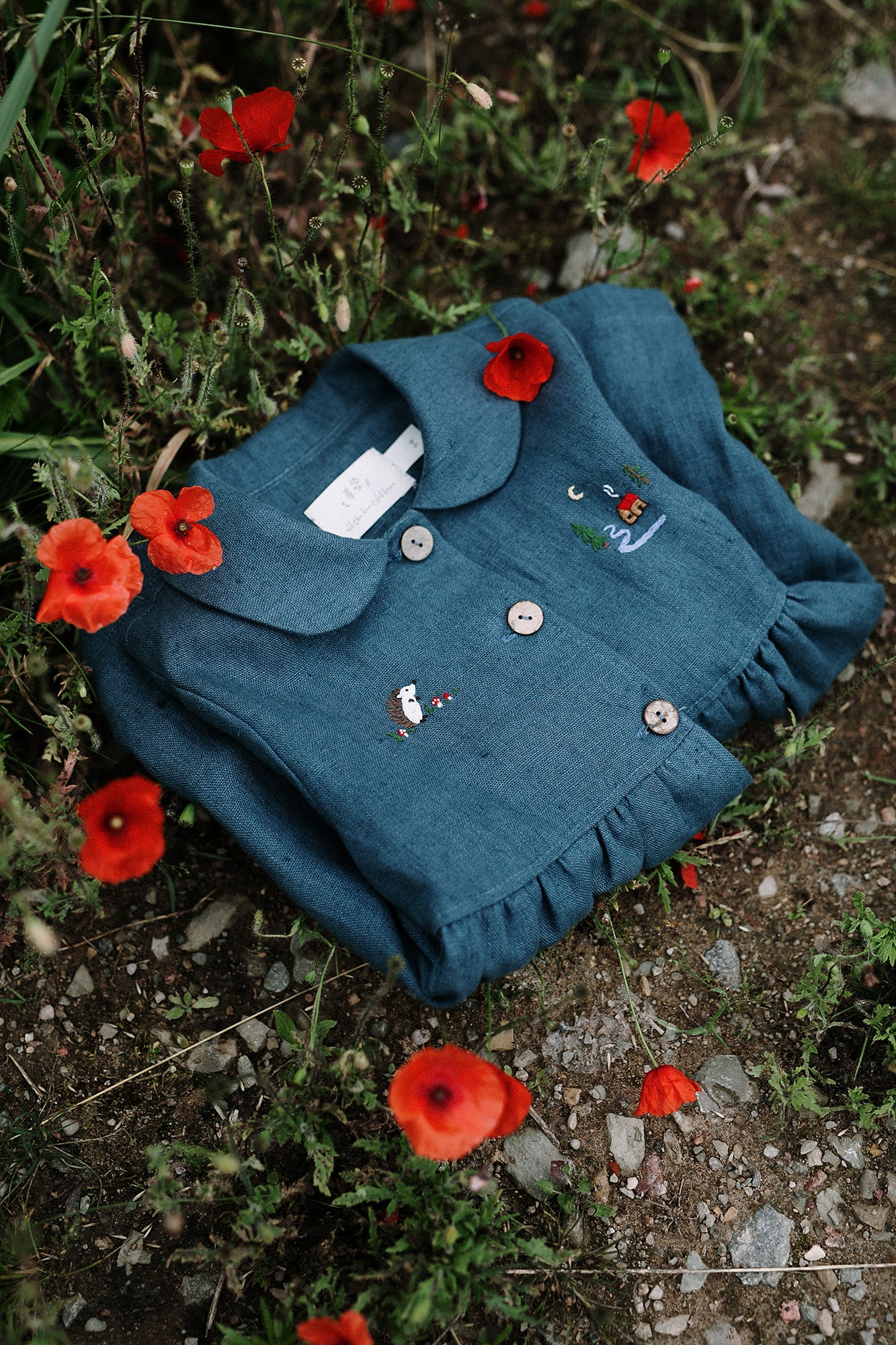 a blue shirt with buttons on it laying in a field of flowers