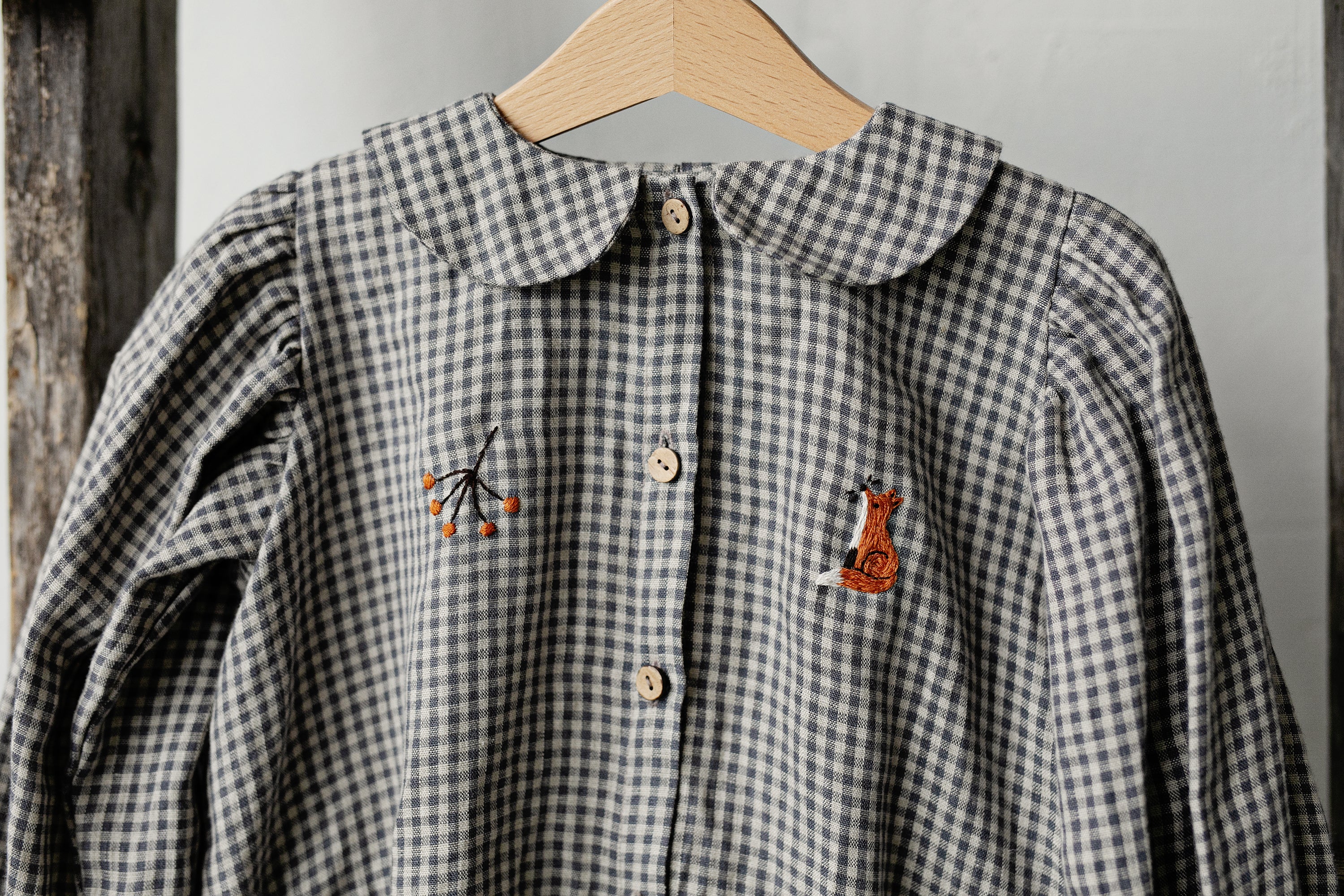 a blue and white checkered shirt hanging on a wooden hanger