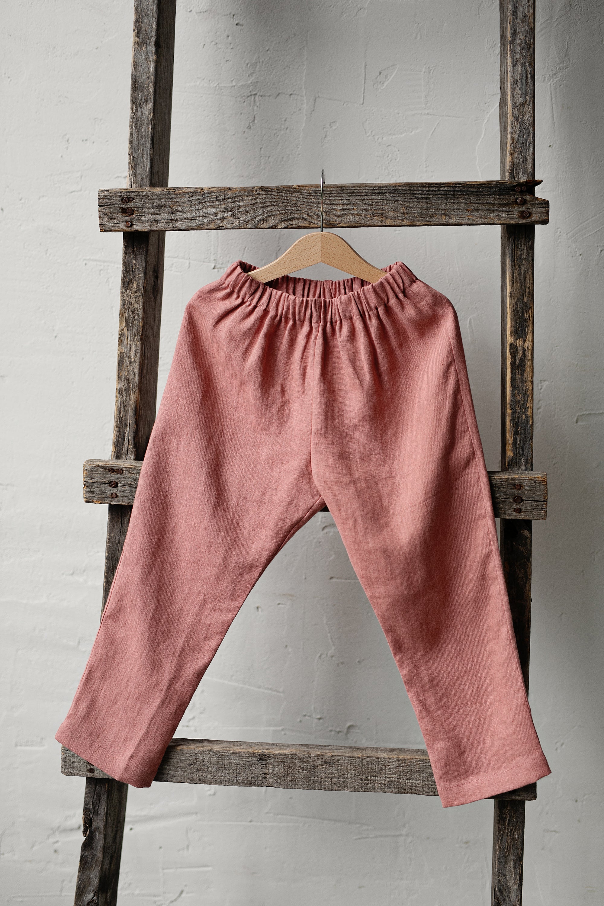 a pink pants hanging on a wooden ladder